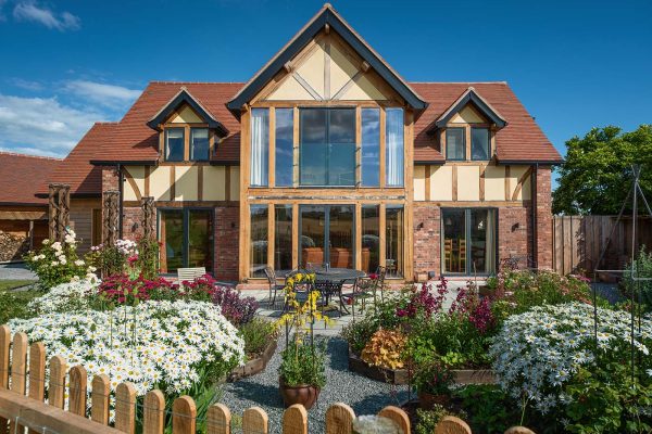 Beautiful oak framed home with flower garden in foreground.